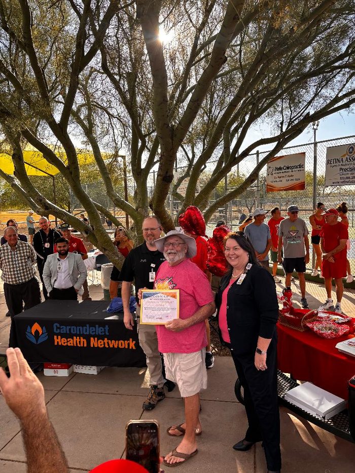 Charlie Corle holds his certificate alongside two representatives of Carondelet Health Network at Udall Park.